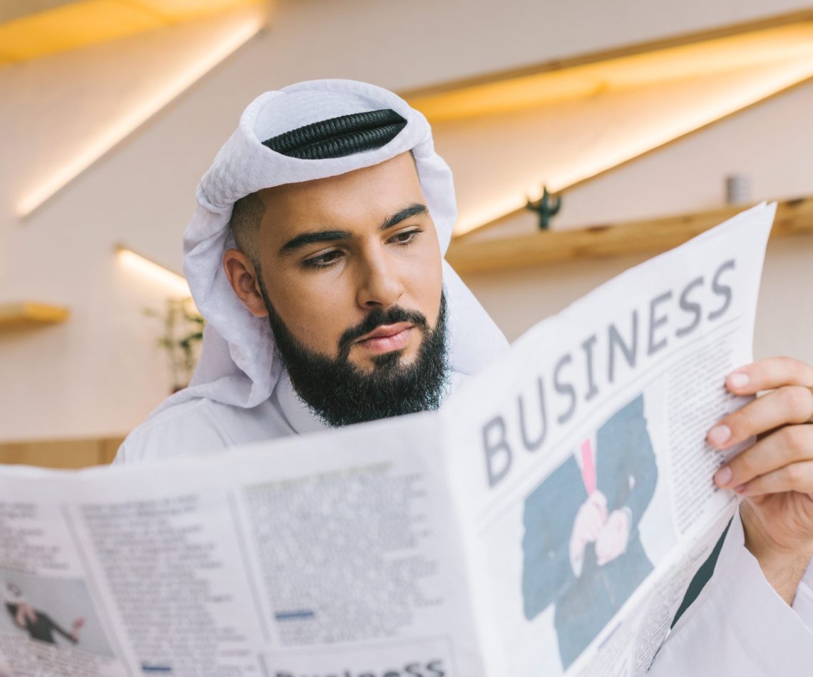 close-up shot of serious muslim businessman reading newspaper