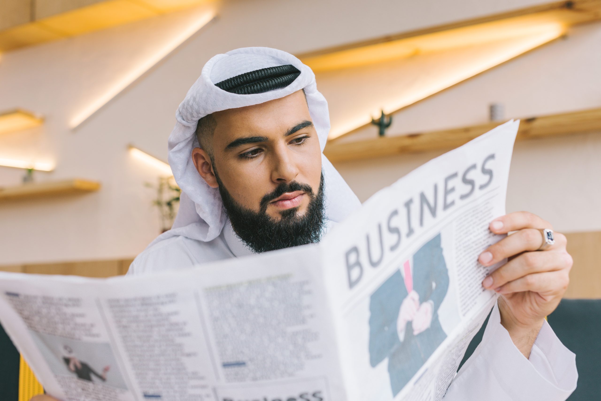 close-up shot of serious muslim businessman reading newspaper