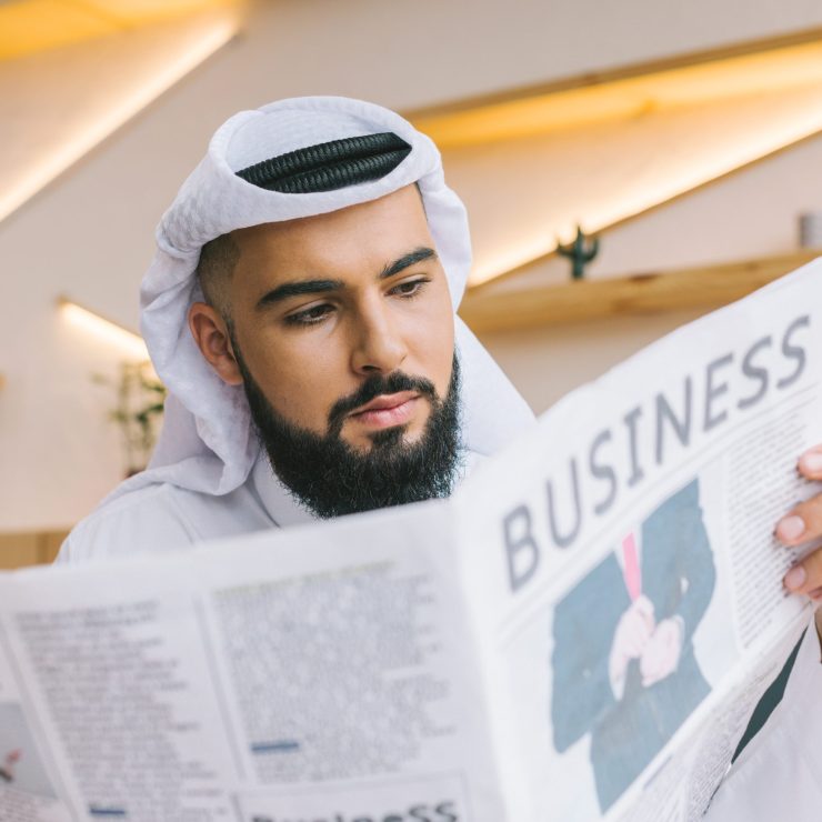 close-up shot of serious muslim businessman reading newspaper