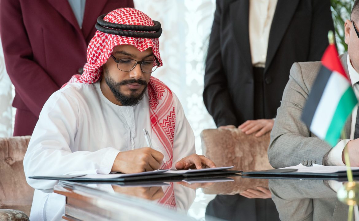 Confident Arabian businessman or delegate in national clothes signing contract