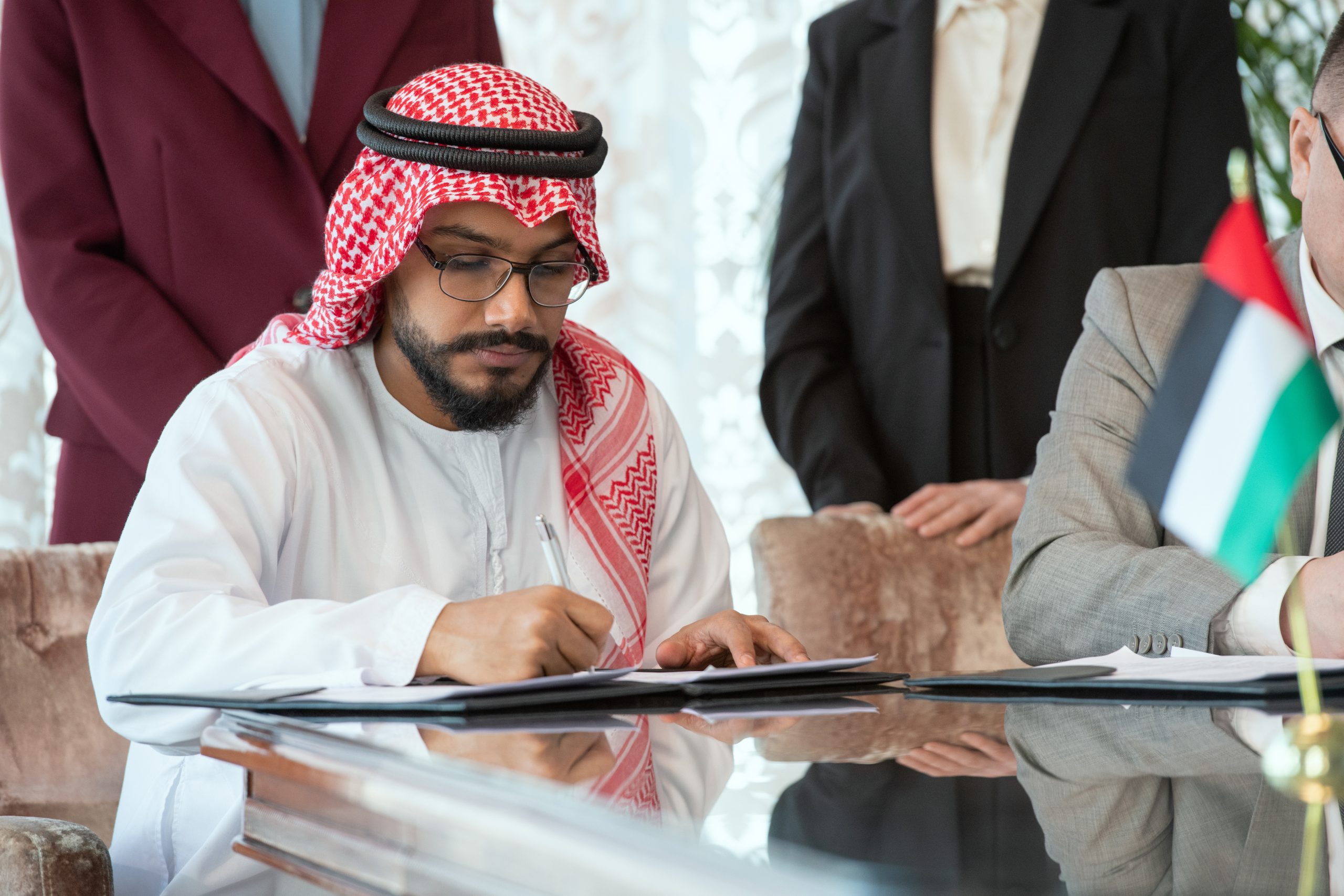 Confident Arabian businessman or delegate in national clothes signing contract