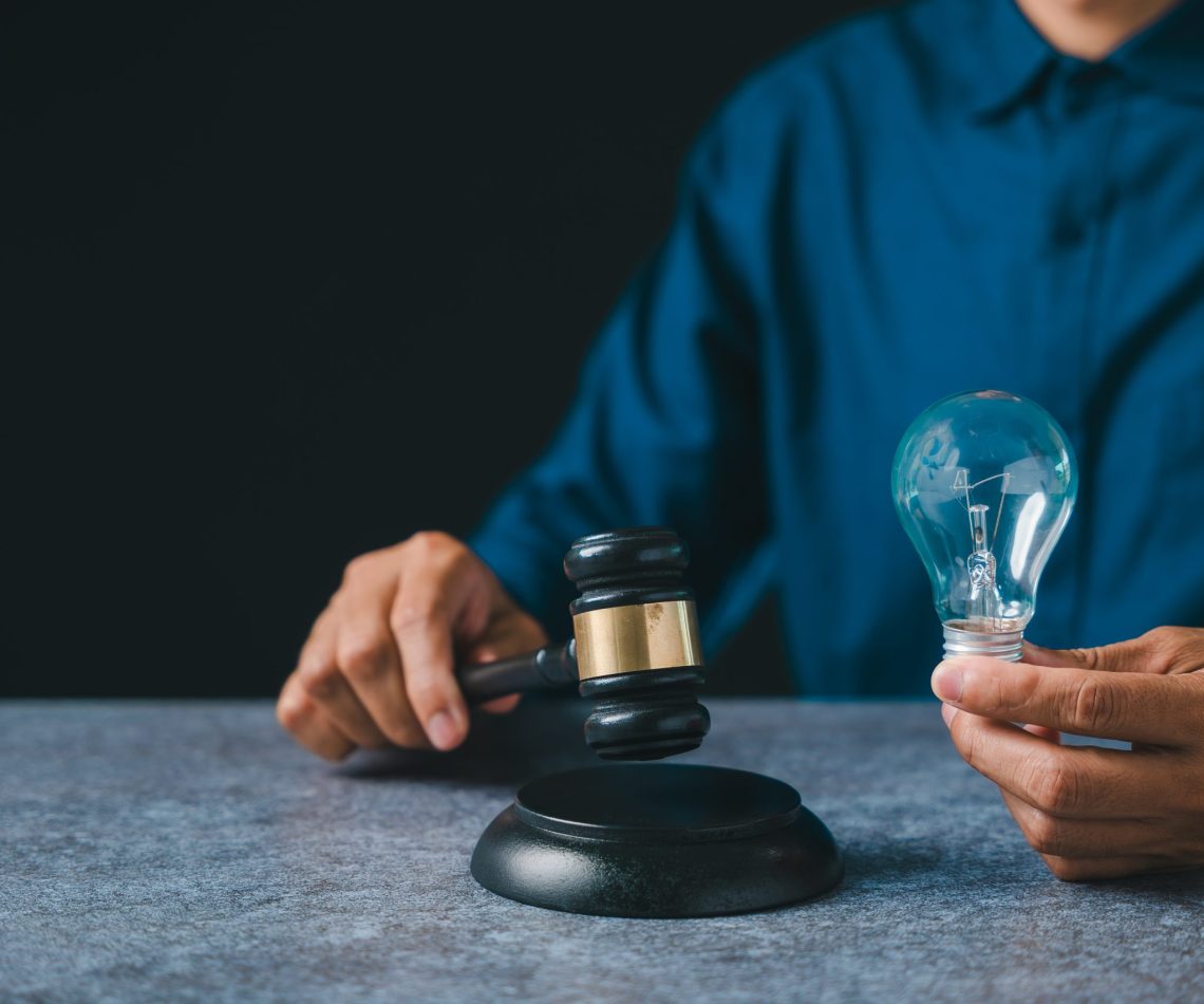 Patent intellectual property bulb light idea concept law legal protect business, person holds judge gavel plus light bulb ensuring protection, innovation security for creators
