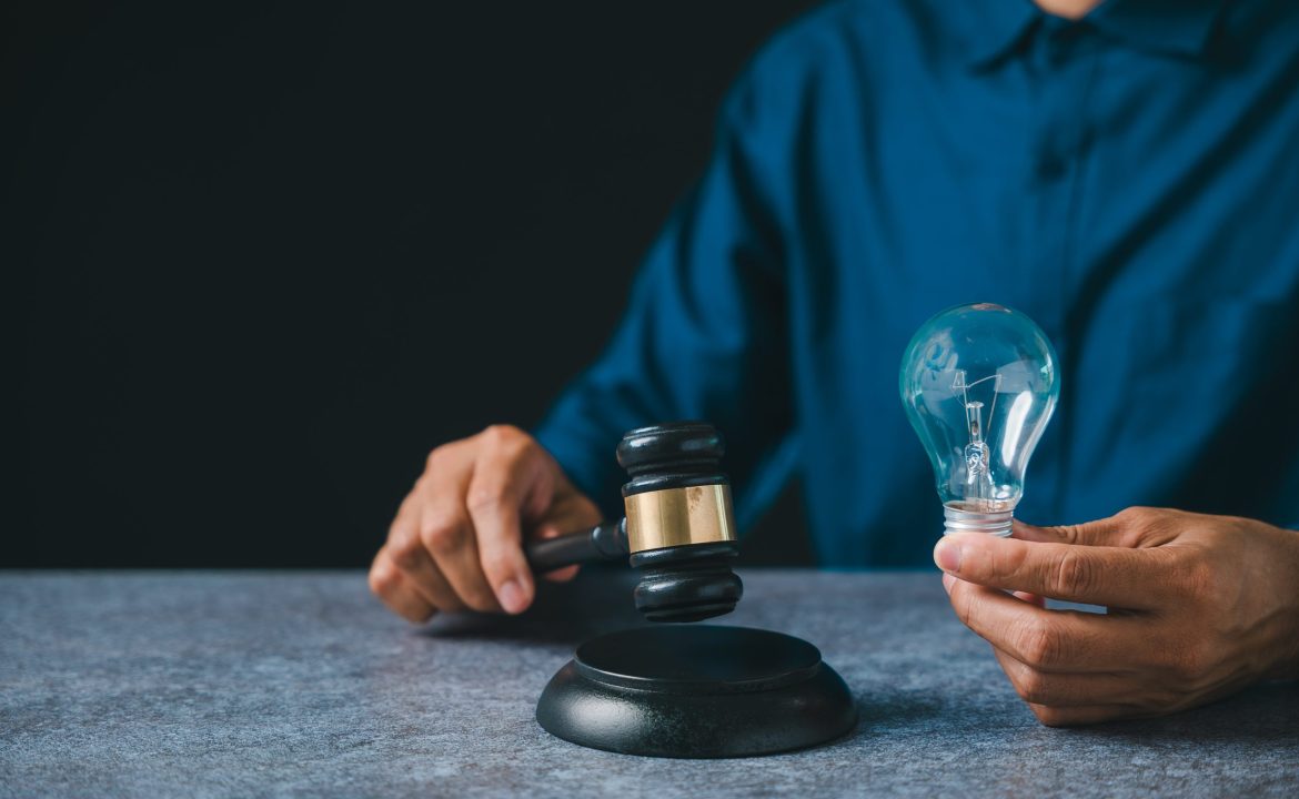 Patent intellectual property bulb light idea concept law legal protect business, person holds judge gavel plus light bulb ensuring protection, innovation security for creators