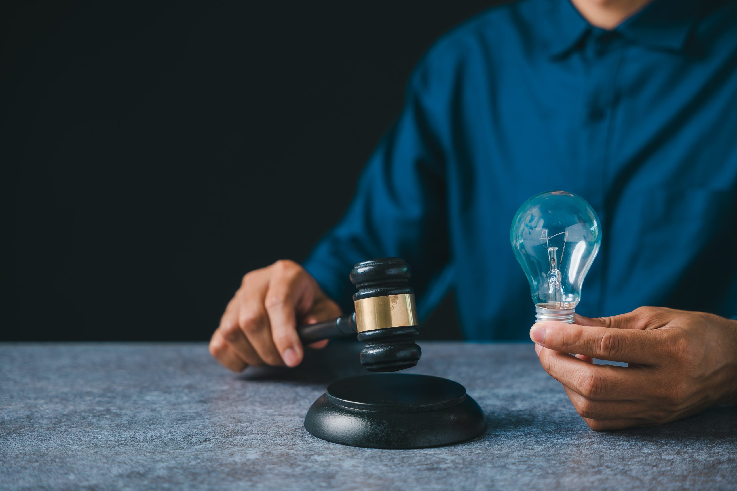 Patent intellectual property bulb light idea concept law legal protect business, person holds judge gavel plus light bulb ensuring protection, innovation security for creators