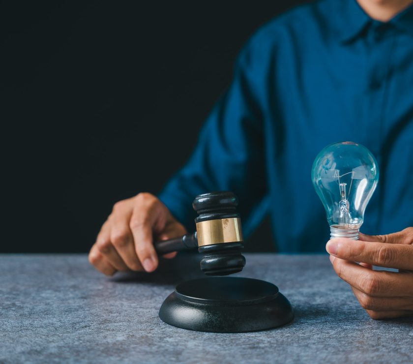 Patent intellectual property bulb light idea concept law legal protect business, person holds judge gavel plus light bulb ensuring protection, innovation security for creators