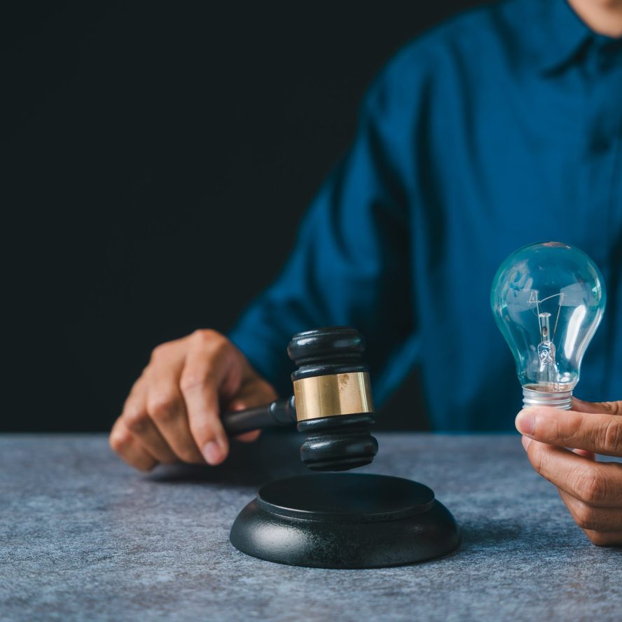 Patent intellectual property bulb light idea concept law legal protect business, person holds judge gavel plus light bulb ensuring protection, innovation security for creators